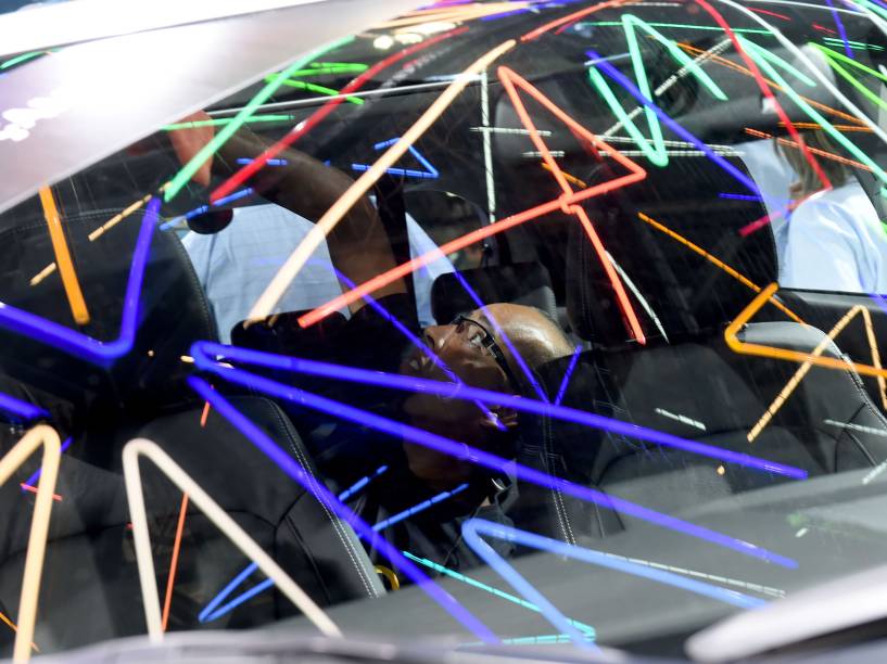 Homem limpa o interior de um carro no Salão do Automóvel, em São Paulo