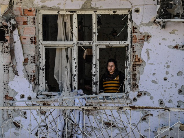 Mulher olha através de uma janela de sua casa em ruínas nesta terça-feira (08), no Dia Internacional da Mulher em Cizre, na Turquia