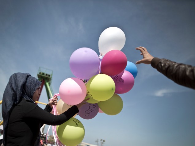 Uma mulher palestina segura balões com frases sobre "direitos das mulheres" para comemorar o Dia Internacional da Mulher, nesta terça-feira (08), em um parque na Cidade de Gaza