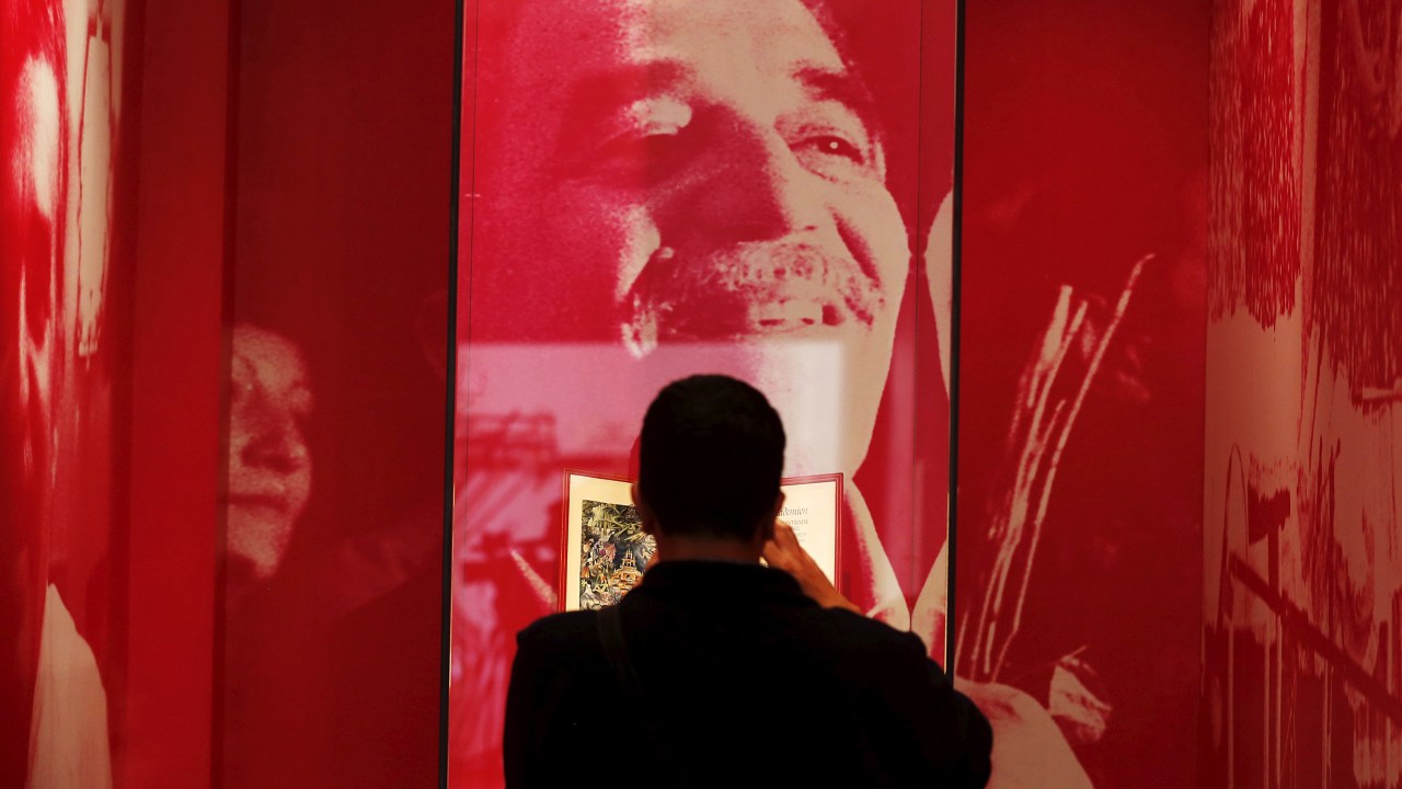 Homem tira fotos na frente de um retrato do escritor colombiano Gabriel García Márquez durante uma exposição na Biblioteca Nacional, em Bogotá