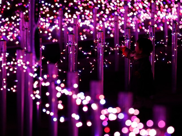 Garoto toca em iluminações de Natal compostas por três milhões de luzes de Led, em um parque de diversões de Tóquio, no Japão 