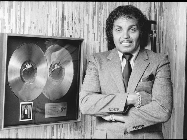 Joseph Jackson, pai e gerente do conjunto The Jackson Five, posa ao lado do prêmio de platina duplo , em 1982