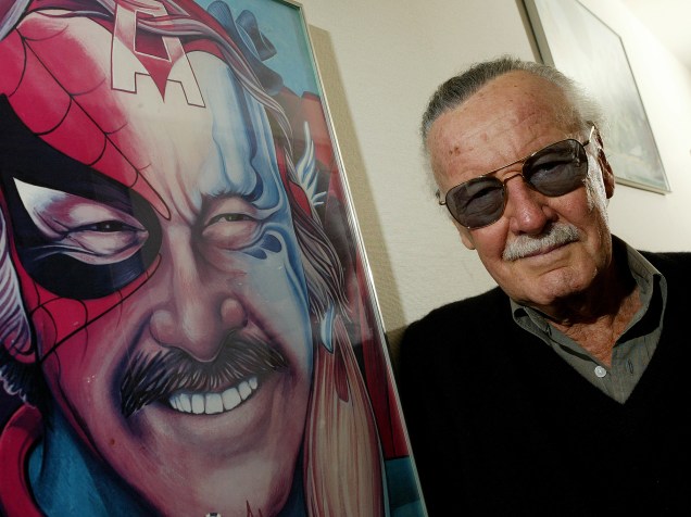 Stan Lee posa em seu escritório, em Beverly Hills, na California, ao lado de um quadro que o representa junto com algumas das personagens criadas ao longo de sua carreira, em 2004