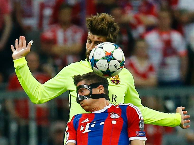 O atacante Robert Lewandowski do Bayern de Munique, divide pelo alto com o zagueiro Gerard Piqué do Barcelona
