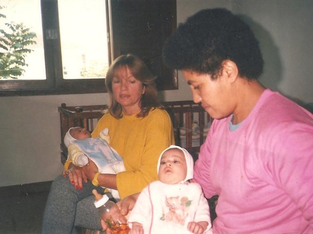 Charlotte (bebê) no colo da mulher que encontrava famílias estrangeiras para adotar as crianças, no Lar da Criança Menino Jesus