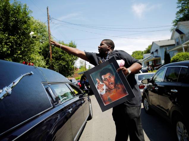 Um homem joga uma rosa sobre o carro fúnebre com o corpo de Muhammad Ali durante o cortejo da lenda do boxe em Louisville, Kentucky - 10/06/2016