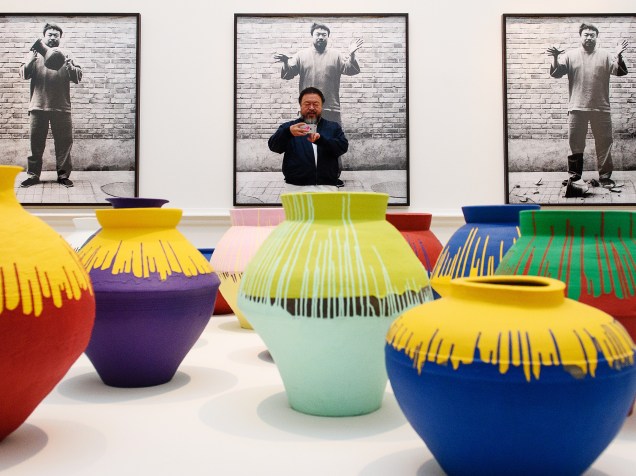 O artista chinês Ai Weiwei posa junto à sua obra Vasos Coloridos em exposição na Royal Academy of Arts em Londres