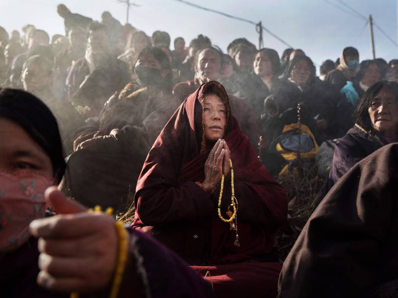 Monge faz orações entre budistas em uma encosta durante sessão de cânticos matinais