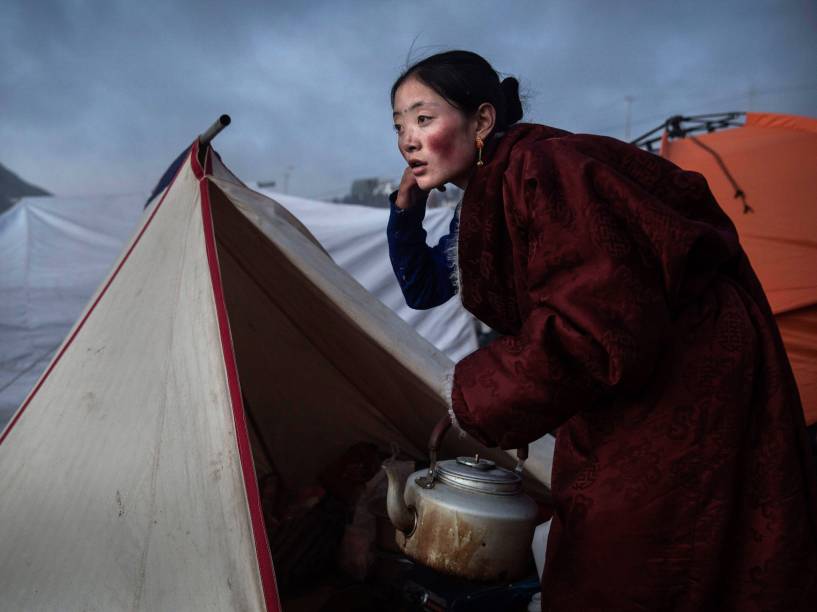 Mulher nômade budista tibetana prepara chá no crepúsculo após uma sessão de cânticos