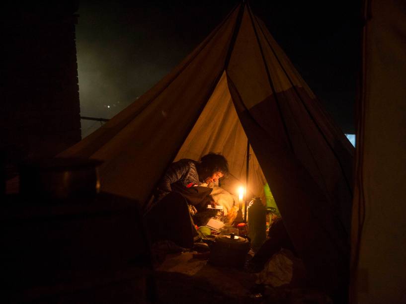Devotos budistas nômades leem um livro religioso em sua barraca dentro um acampamento após uma sessão de cânticos