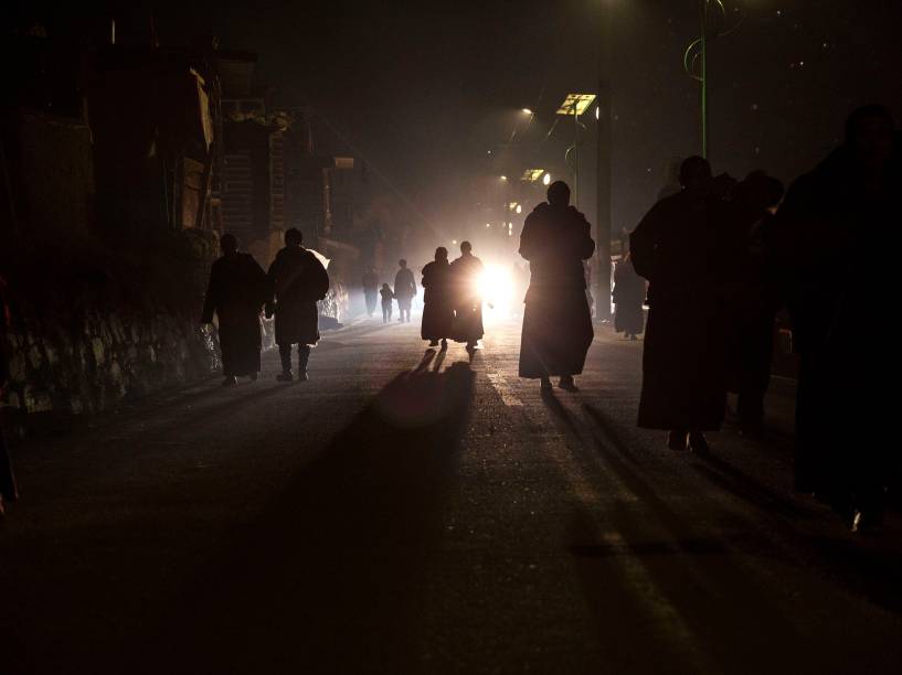 Budistas tibetanos caminham para casa depois de uma sessão de cânticos durante a Assembleia anual da Bem-Aventurança Dharma que celebra a descida de Buda dos céus
