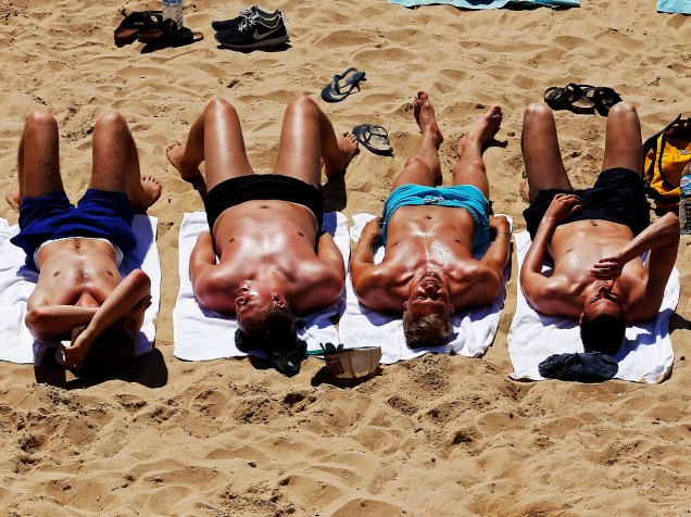 Homens tomam sol em uma praia na aldeia turística de Cascais, nos arredores de Lisboa, em Portugal - 29/06/2015
