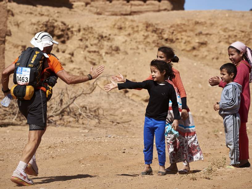  Competidor é saudado por crianças, durante a Maratona das Areias, realizada no sul do Deserto do Saara, no Marrocos