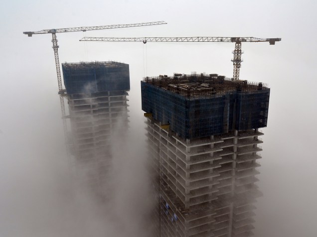 Prédios em construção são vistos entre o nevoeiro em Rizhao, na China