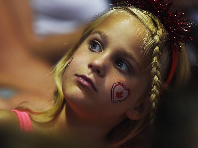 Menina é fotografada enquanto acompanha a primeira sessão da competição por equipes da ginástica artística masculina