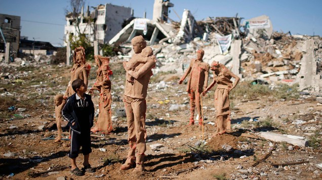 Criança observa estátuas feitas de fibra de vidro e cobertas com argila, que representam palestinos que fugiram de suas casas durante bombardeios israelenses nos conflitos que ocorreram entre julho e agosto deste ano em Gaza