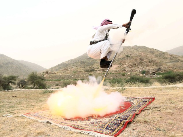 Homem dispara uma arma enquanto dança durante uma tradicional excursão comemorativa, próximo à cidade de Ta’if, na Arábia Saudita