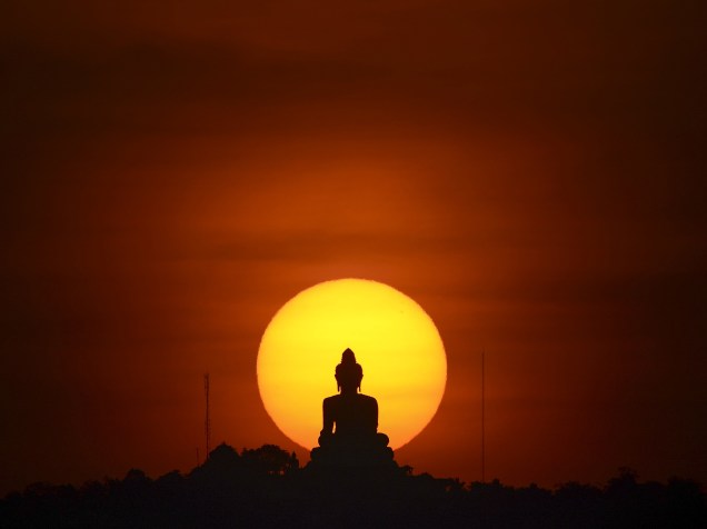 Sol se põe atrás de uma estátua de Buda em Phuket, na Tailândia