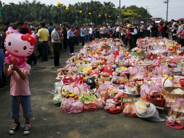Criança segura um balão da personagem Hello Kitty enquanto milhares de pessoas participam de uma cerimônia de culto em respeito aos antepassados em Taoyuan, Taiwan - 04/04/2016