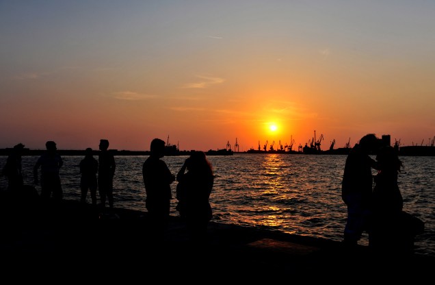 Na Grécia, turistas observam o pôr-do-sol no porto de Salonica, região norte do país