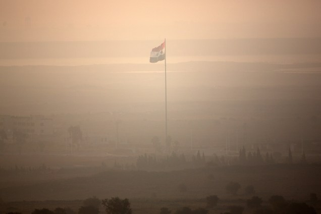 Bandeira da Síria é fotografada momentos antes de ser removida durante disputa entre forças leais a Bashar al-Assad e militantes rebeldes perto da fronteira de Quneitra