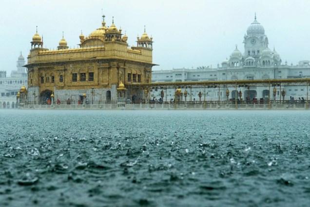Devotos sikh prestam homenagens durante forte chuva no Santuário Dourado em Amritsar, na Índia
