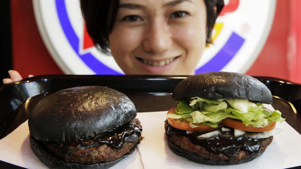 Funcionária do Burger King posa com o novo sanduíche chamado "kuro hambúrguer", preparado com ingredientes de cor preta, em Tóquio, no Japão