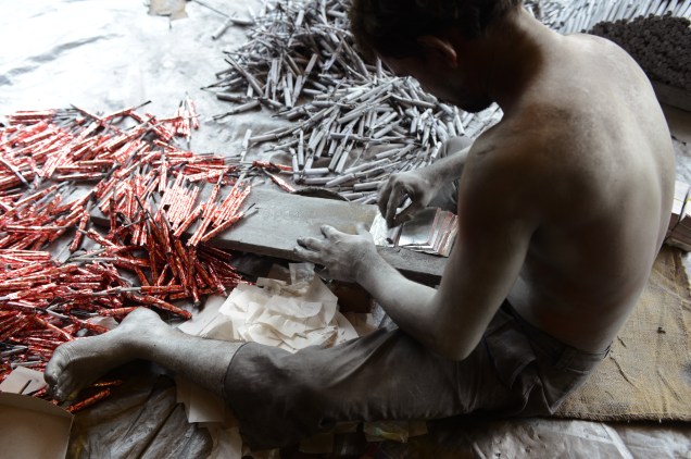 Indiano trabalhador prepara fogos de artifício para festival Hindu, em Ahmedabad, Índia