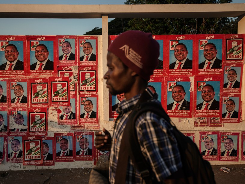 Um homem passa por uma parede rebocada com cartazes eleitorais da Frente de Libertação de Moçambique (FRELIMO), o partido do candidato presidencial, Filipe Nyusi, em Maputo, Moçambique, nesta quinta-feira (09)
