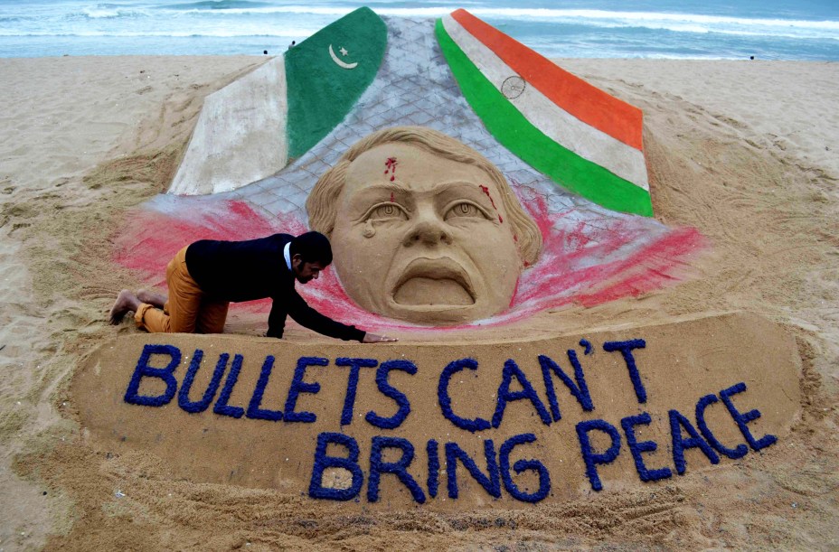 Artista de areia indiano, Sudarsan Pattnaik, dá os últimos toques na sua escultura sobre os conflitos entre Índia e Paquistão. No chão da praia de Puri, na Índia, Bullets cant bring peace, do inglês, Armas não podem trazer paz