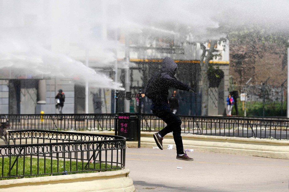 Estudante chileno corre de jato dágua disparado pela polícia durante protesto contra o governo por melhorias no sistema educacional do Chile, em Santiago