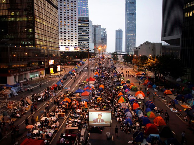 Protestantes pró-democracia assistem conversa entre estudantes líderes do movimento e oficiais da cidade através de uma televisão posta perto da sede do governo em Hong Kong