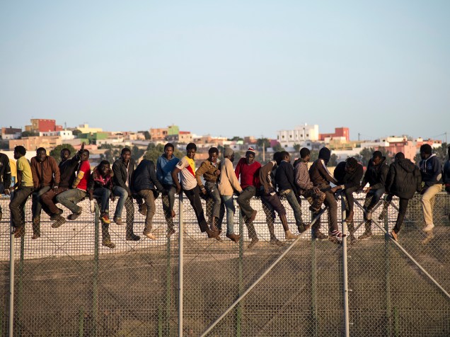 Na imagem, imigrantes são vistos sobre uma cerca na fronteira que separa Marrocos do enclave espanhol de Melilla, na região norte da África. Segundo informações do governo local, o fluxo de imigrantes ilegais lutando para chegar à Espanha já passa do dobro do registrado no ano passado