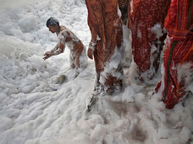 Devoto hindu empurra a espuma para liberar espaço para outros fiéis nas águas poluídas do rio Yamuna, durante o festival religioso Chatt Puja, em Nova Delhi, na Índia