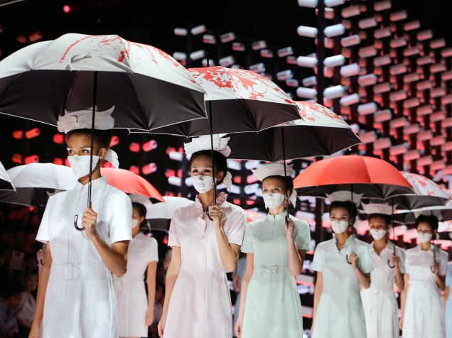 Modelos usando máscaras e guarda-chuvas são vistas durante a Semana da Moda da China, em um desfile na cidade de Pequim