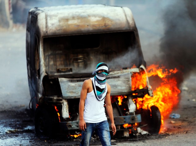 Um manifestante palestino incendeia um carro durante os confrontos com as forças de segurança nacional, em Jerusalém, capital de Israel