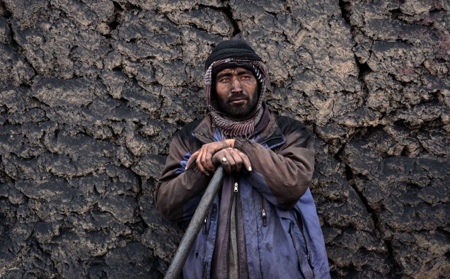 Trabalhador afegão espera para carregar uma pilha de carvão em um caminhão nos arredores de Mazar-i-Sharif. A econômia do país tem melhorado significativamente desde a queda do regime talibã, em 2001, em grande parte devido a assistência internacional