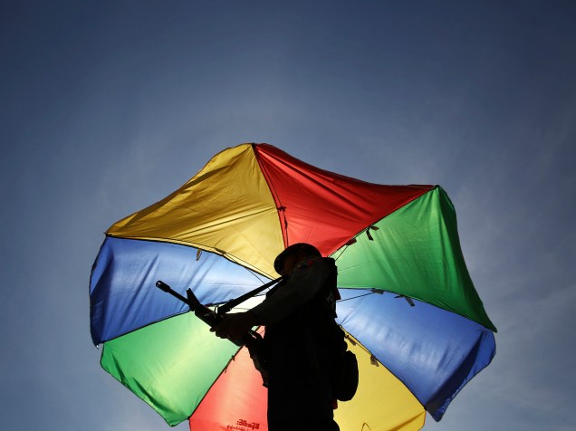 Policial com um guarda-chuva colorido patrulha a estrada que levava até local onde foi realizado o encontro de líderes dos países Leste Asiático (Asean) em Naypyitaw, Mianmar. O encontro também contou com a participação do presidente dos Estados Unidos, Barack Obama - 10/11/2014