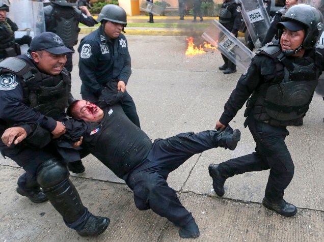 Policial ferido é resgatado durante confrontos com manifestantes em um protesto provocado pelo massacre de 43 estudantes mexicanos, nas proximidades do aeroporto de Acapulco