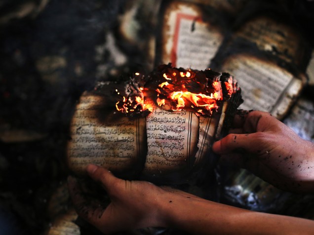 Palestino exibe uma cópia do Alcorão, ainda em chamas dentro de uma mesquita incendiada por colonos israelenses em al-Mughayir, na Cisjordânia - 12/11/2014