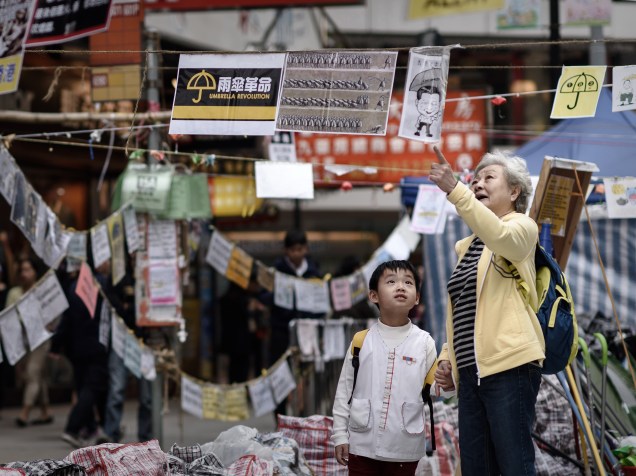 Idosa explica a uma criança o significado dos cartazes criados por manifestantes pró-democracia em um local de protesto em um distrito da Baía de Causeway, em Hong Kong - 14/11/2014