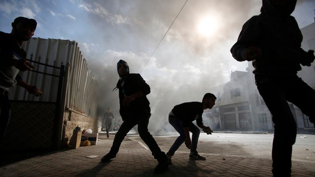 Manifestantes palestinos se preparam para atirar pedras em soldados do Exército israelense durante confrontos na cidade de Hebron - 14/11/2014