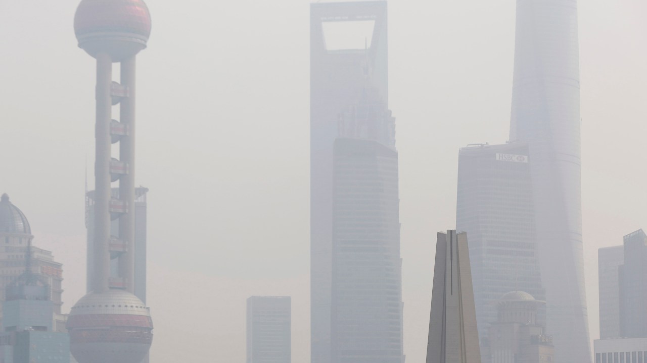Homem usa uma máscara para se proteger da poluição, em uma ponte em frente ao distrito financeiro de Pudong, em Xangai, na China - 17/11/2014
