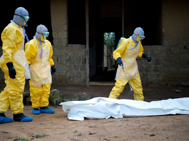 Profissionais de saúde da Cruz Vermelha da Guiné retiram o corpo de uma vítima do vírus Ebola, em Momo Kanedou. Guiné, Libéria e Serra Leoa, foram os mais atingidos pelo epidemia que já matou mais de 5 mil pessoas este ano, segundo a OMS
