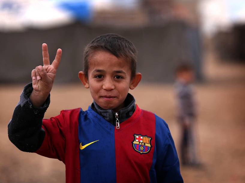 Criança iraquiana faz pose para foto com uma camisa do time espanhol Barcelona, no campo de refugiados de Harsham, região autónoma do Curdistão 