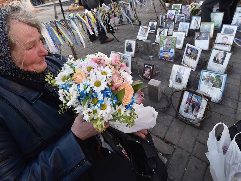 Mulher prende flores no Monumento de Heavenly Hundred, durante a cerimônia memorial em Kiev, na Ucrânia. Dezenas de pessoas se reuniram na Praça da Independência, deixando flores para as mais de 100 pessoas mortas nos confrontos separatistas desde o ano passado 