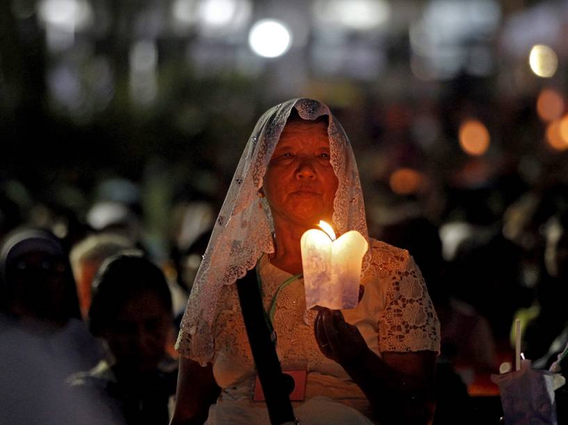 Devota cristã é fotografada segunda uma vela durante suas orações na igreja católica de St. Mary, em Rangum, na Birmânia