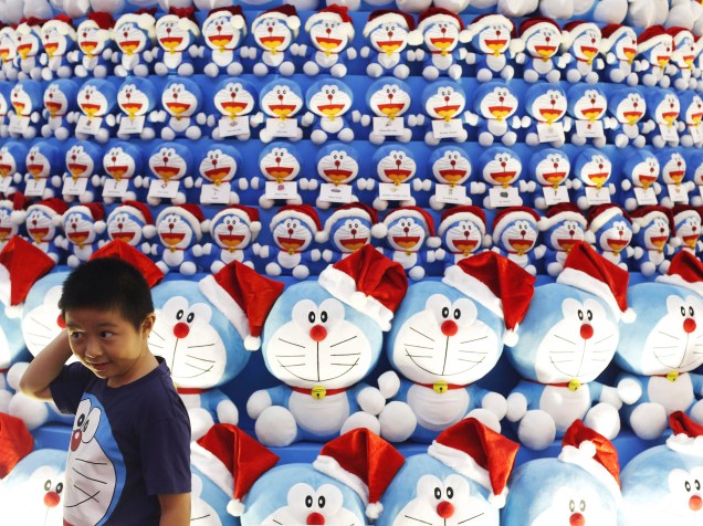 Criança posa para foto em uma árvore de Natal decorada com o personagem de mangá japonês Doraemon, em um shopping no distrito central de negócios em Cingapura - 24/11/2014