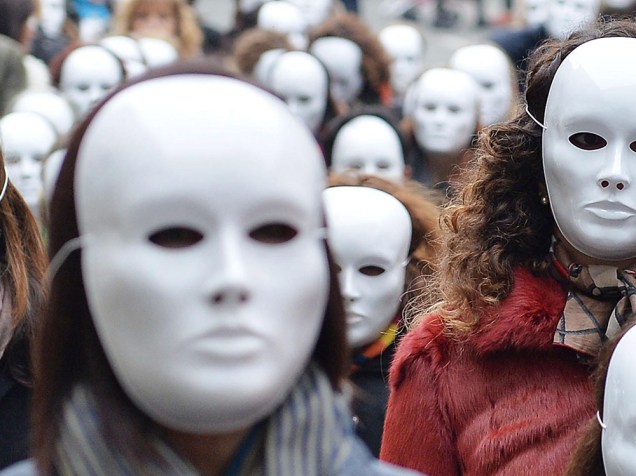 Grupo de mulheres com máscaras brancas no Dia Internacional para a Eliminação da Violência contra a Mulher, em Turim, na Itália
