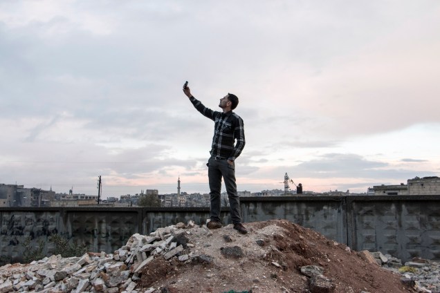Um homem tentou obeter sinal de telefone subindo num morro em Aleppo. Mais de 200 mil pessoas morreram no território sírio desde o início do conflito em março de 2011, segundo a ONU
